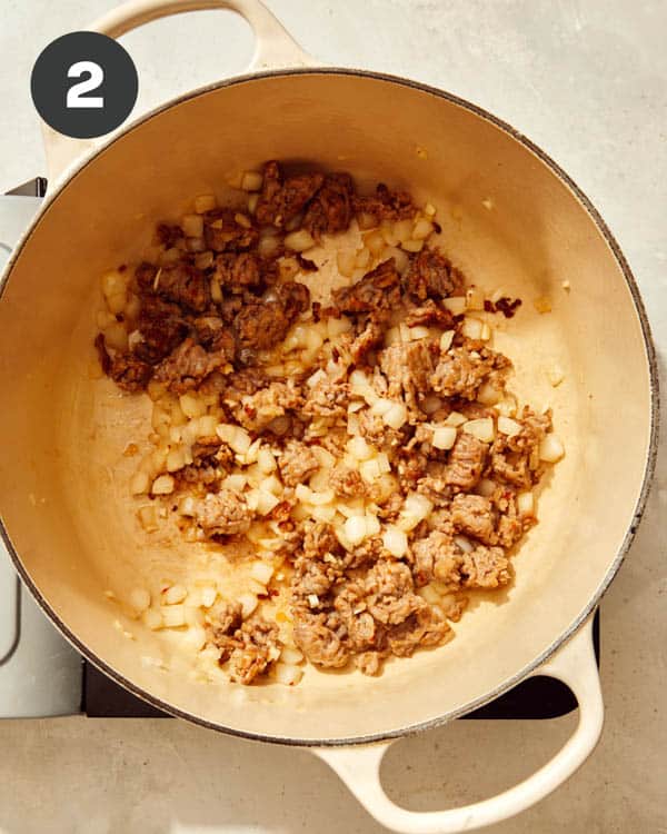 Sausage and onions cooking in a pot to make one pot pasta. 