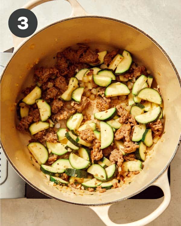 Sausage and onions in a pot with zucchini. 