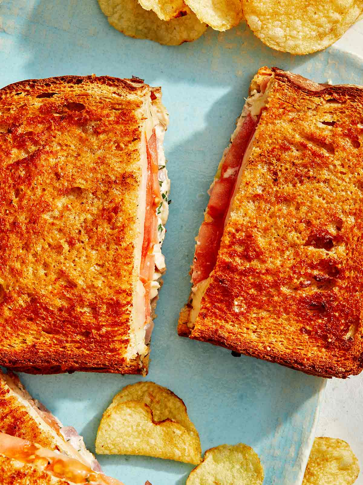 Air fryer tuna melt recipe cut with potato chips on the side. 