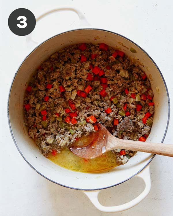 Cooking down meat to make a bolognese sauce in a pot.