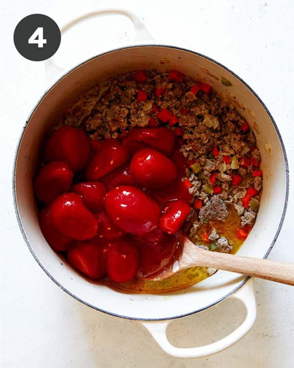 Tomatoes added into a stock pot to make a bolognese sauce.