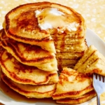 Buttermilk pancakes on a plate with a slice taken out of the stack.