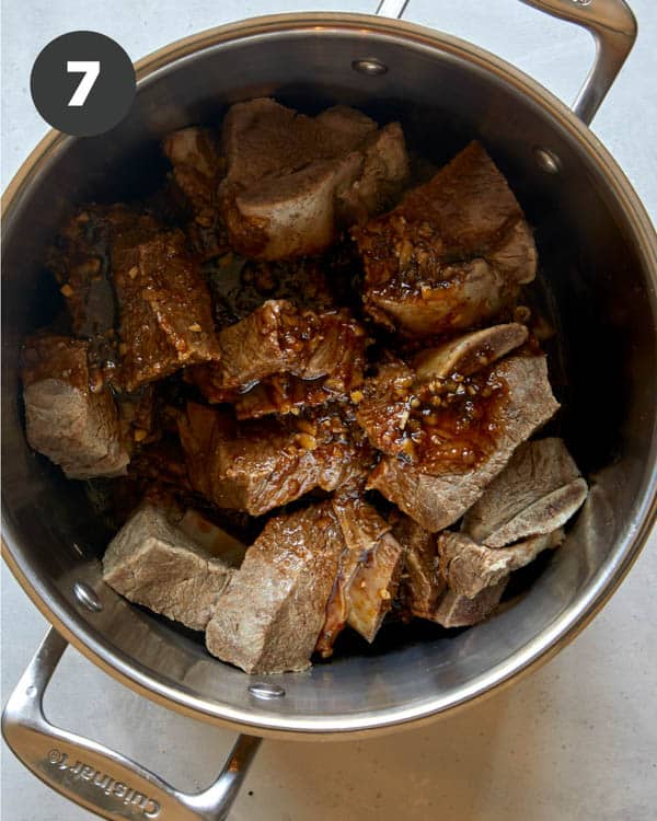 Short ribs in a pot with braising liquids. 