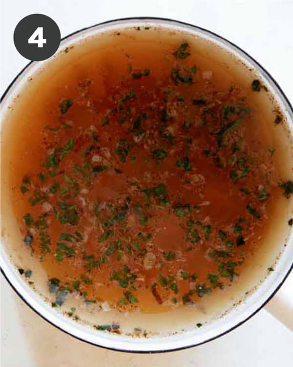 Adding stock to a pot with sautéd garlic, shallots and herbs for Pumpkin Soup. 