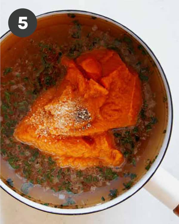 Adding Pumpkin Purée in a pot with other ingredients to make Pumpkin Soup.