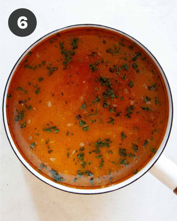 Combining the pumpkin purée with the stock in a pot for Pumpkin Soup. 