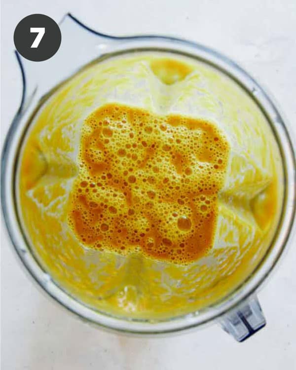 Pumpkin soup mixture in a blender shot overhead. 
