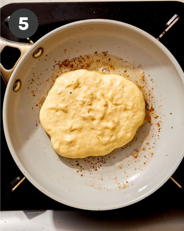 Buttermilk pancakes cooking in a skillet. 