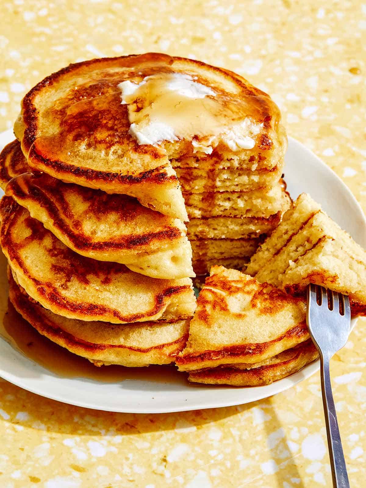 Buttermilk pancakes on a plate with a slice taken out of the stack. 