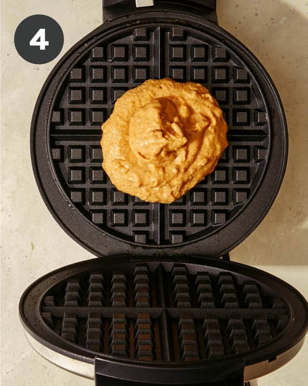 Pumpkin waffles batter in a waffle iron. 