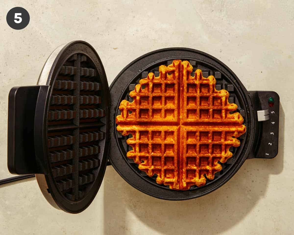 Pumpkin waffles being made in a waffle iron. 