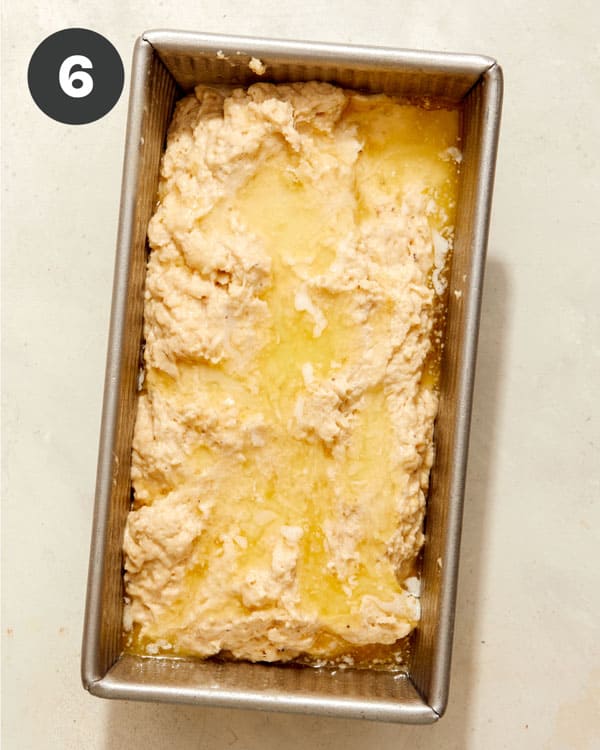 Beer bread dough in a loaf pan with melted butter poured over it. 