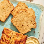 Beer bread slices on a plate with butter on the side.