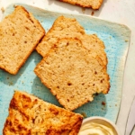 Beer bread slices on a plate with butter on the side.