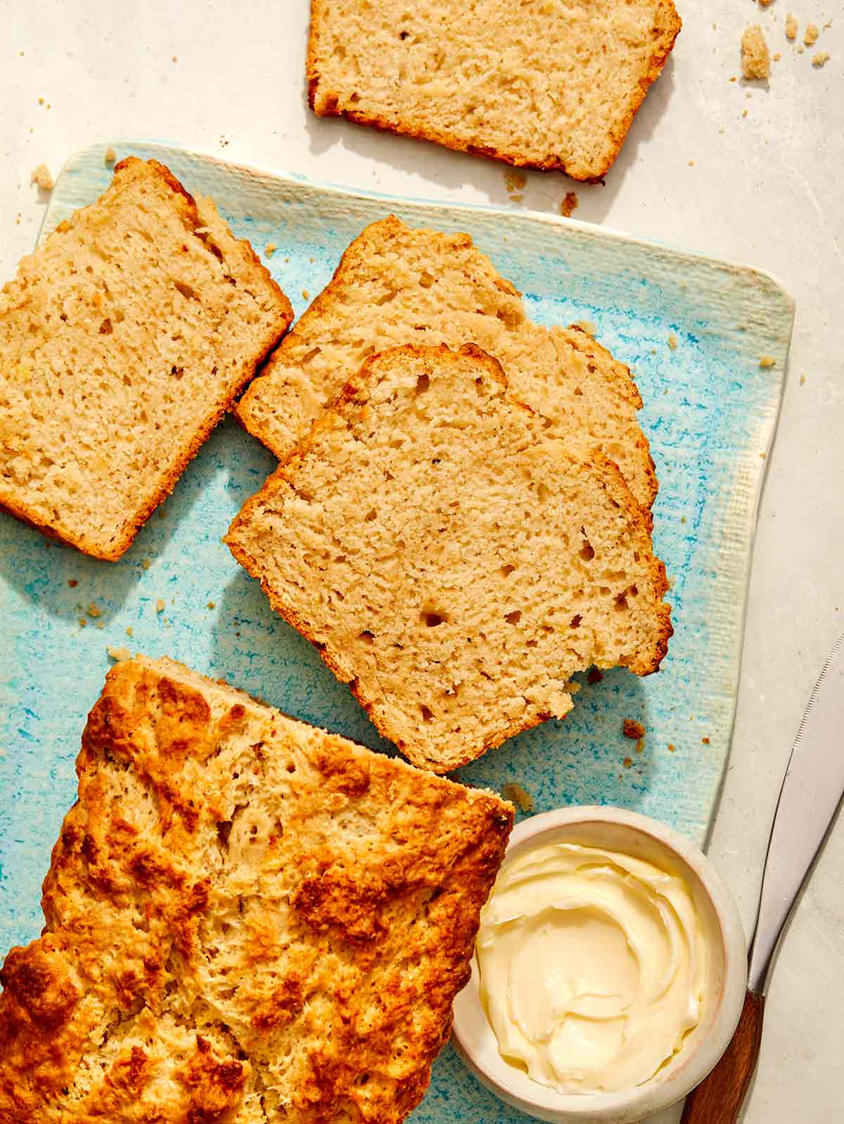 Beer bread slices on a plate with butter on the side. 