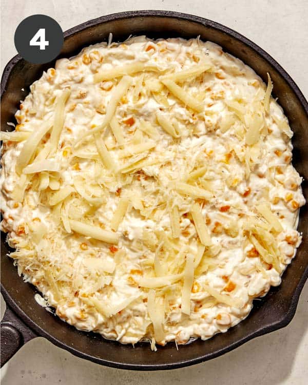 Corn dip in a skillet with cheese on top. 