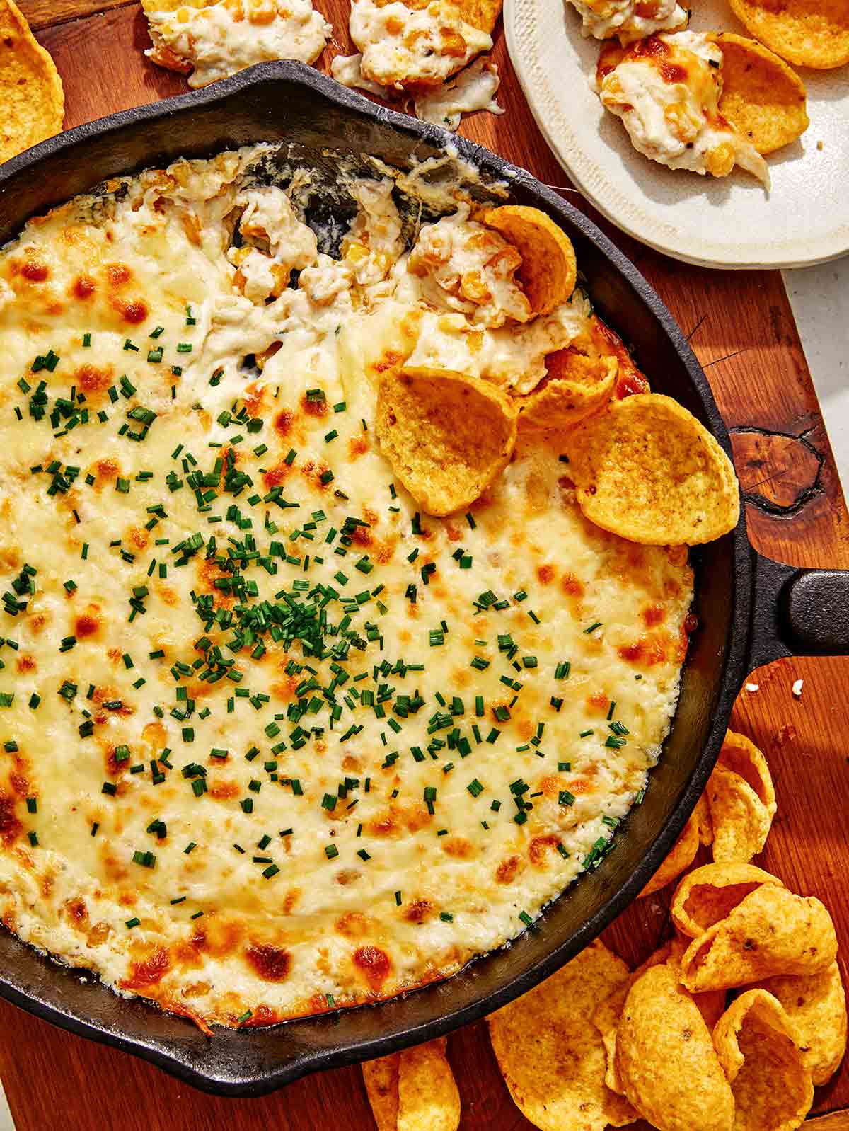 Corn dip in a skillets with chips on the side.