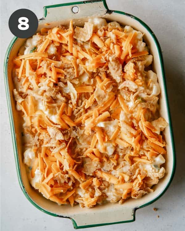 Creamy baked cauliflower topped with cheese and onions to be baked.