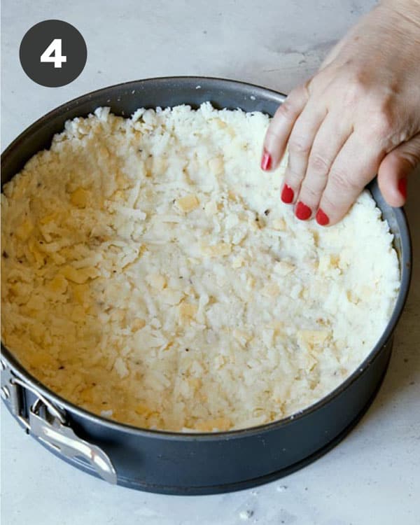 Hash brown crust mixture being pressed into a spring form pan on the edges.