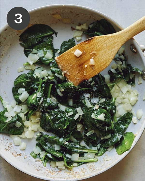 Spinach and onions in a skillet.