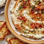 Whipped goat cheese in a bowl with crostini on the side.