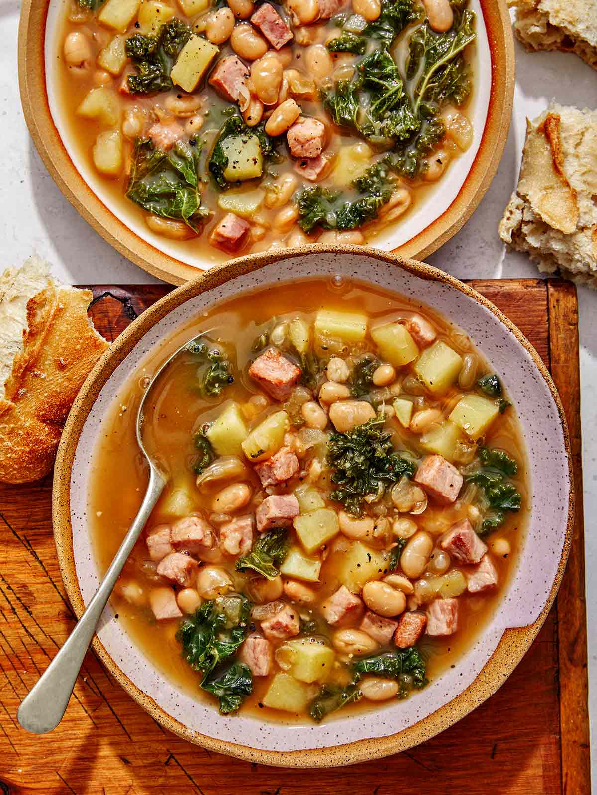 White bean and kale soup recipe in two bowls with bread on the side. 