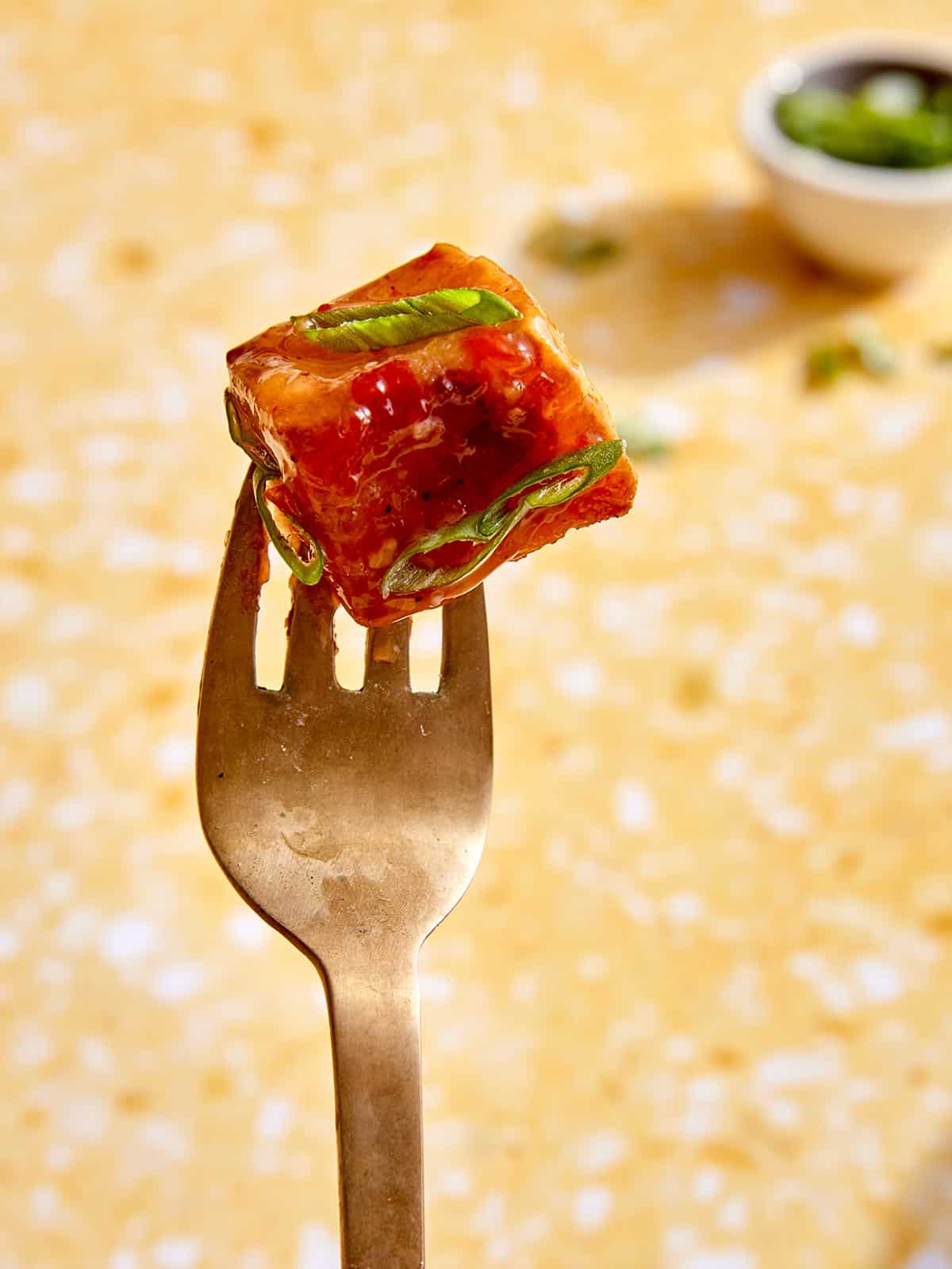 A cube of crispy air fryer tofu on a fork. 