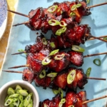 Air fryer chicken skewers with green onions on top.