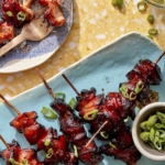 Air fryer chicken skewers on a platter with green onions.