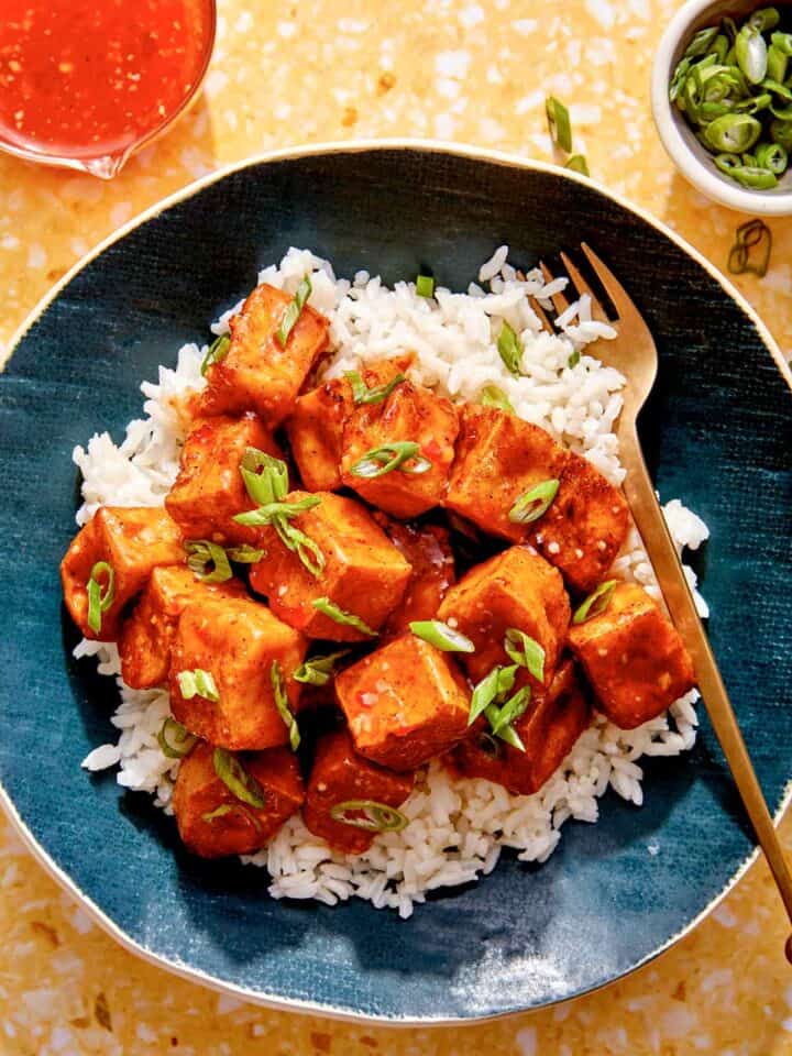 Crispy air fryer tofu with a sweet chili sauce on a bed of rice.