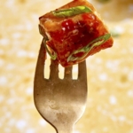 A cube of crispy air fryer tofu on a fork.