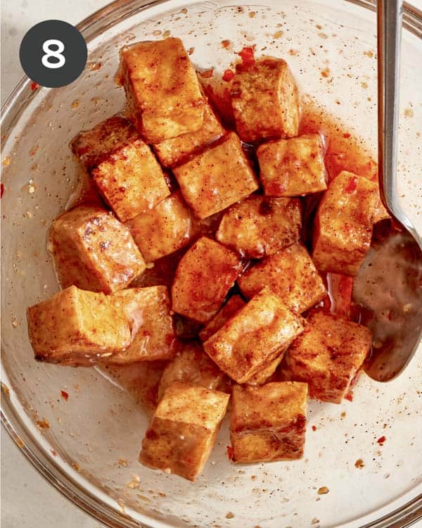 Crispy air fryer tofu being tossed in a sweet chili sauce. 