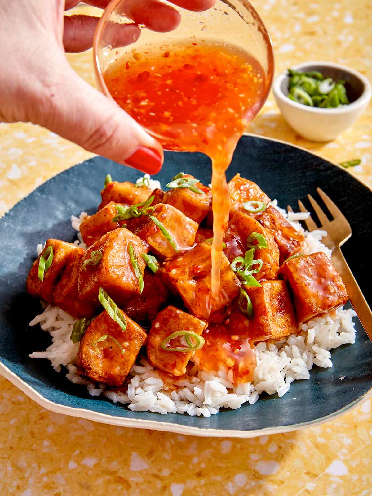 Crispy air fryer tofu with sweet chili sauce being poured all over. 