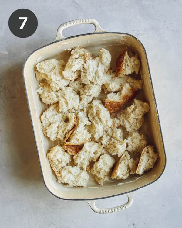 Torn bread in a baking dish for the base layer of a strata.