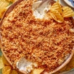 Fried pickle dip in a bowl with potato chips on the side.