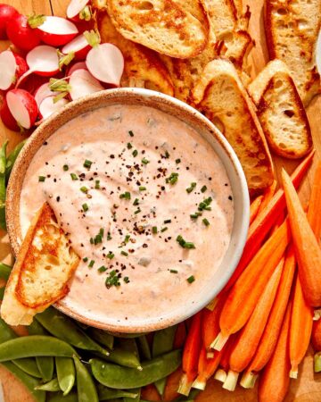 Spicy dill pickle dip on a bowl with ingredients on the side.
