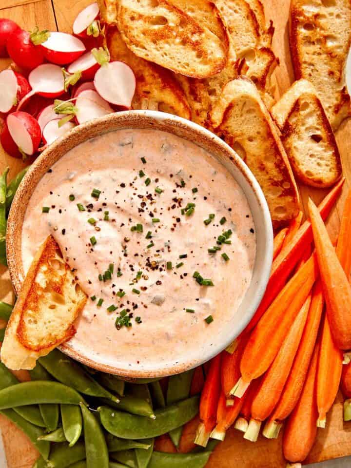 Spicy dill pickle dip on a bowl with ingredients on the side.