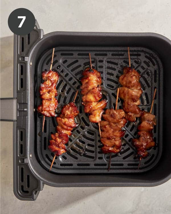 Air fryer chicken skewers cooking in a basket.