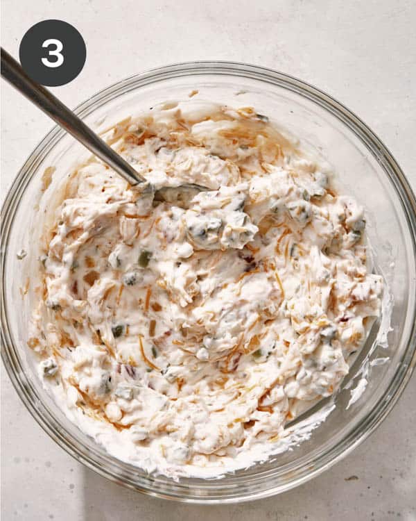 Baked potato dip mixed together in a glass bowl.