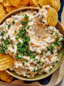 Baked potato dip recipe with potato chips dipped in it.