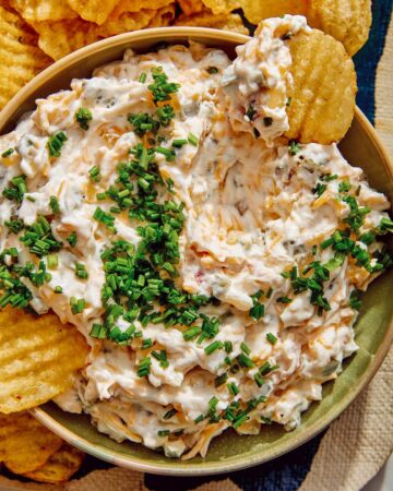 Baked potato dip recipe with potato chips dipped in it.