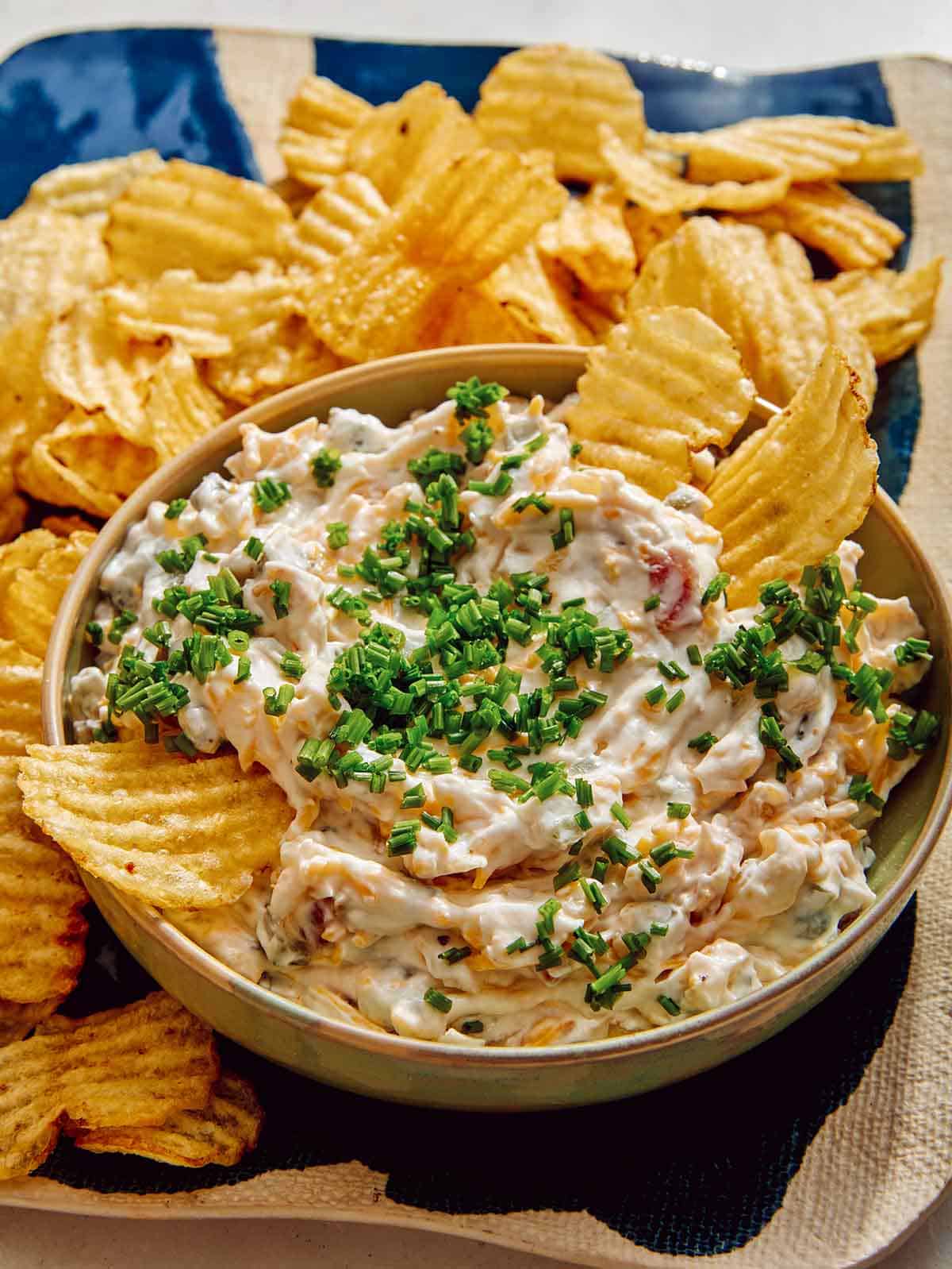 Baked potato dip in a bowl with potato chips on the side. 