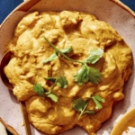 Chicken korma in a bowl with cilantro on top.