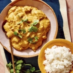 Chicken korma on a plate with rice and a fork.