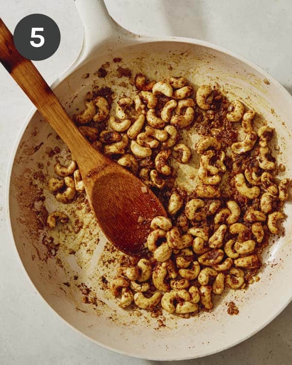 Cashews with onions and garlic cooking in a skillet. 