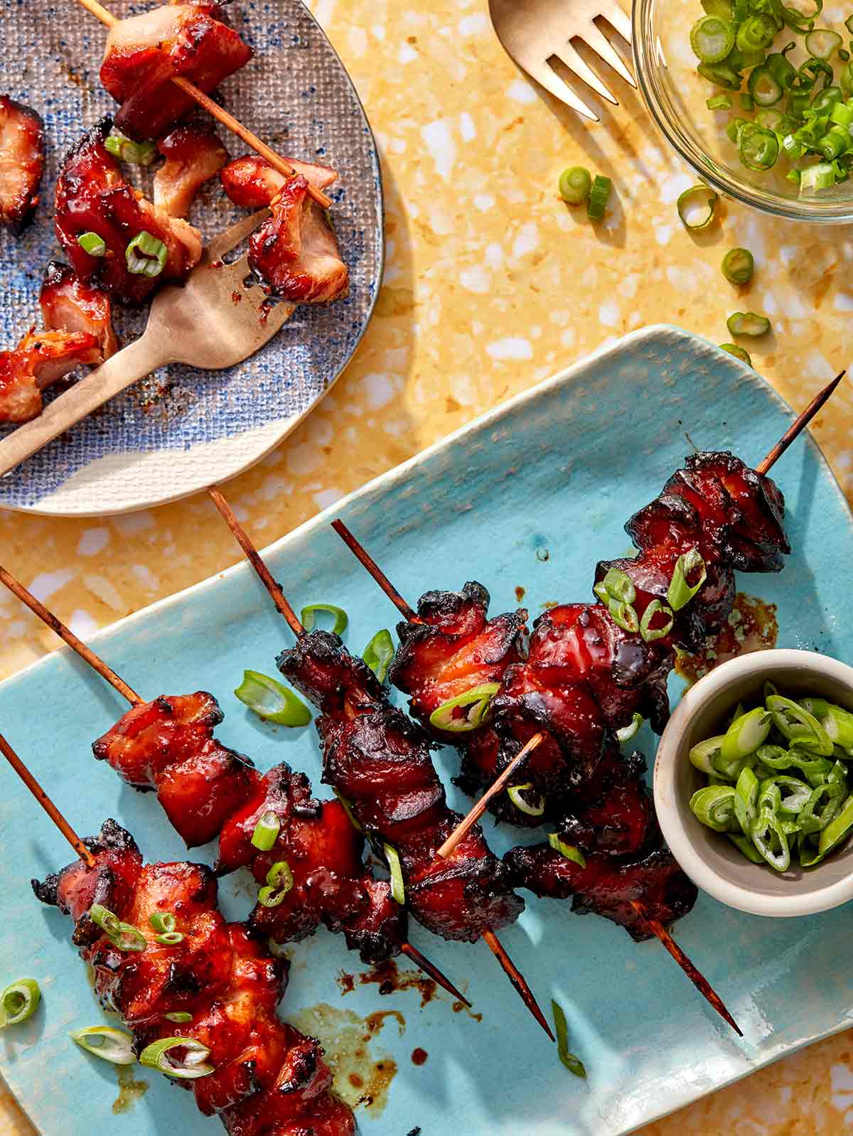 Air fryer chicken skewers on a platter with green onions.