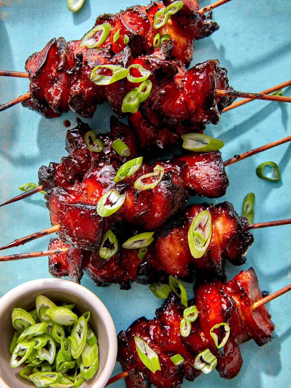 Air fryer chicken skewers with green onions on top.