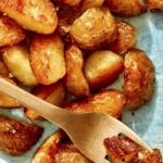 Crispy roasted potatoes on a platter with a fork.