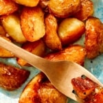 Crispy roasted potatoes on a platter with a fork.