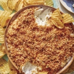 Fried pickle dip in a bowl with potato chips on the side.